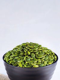 Close-up of green peas in container against white background