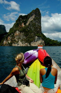 Women sitting on boat in lake against mountains