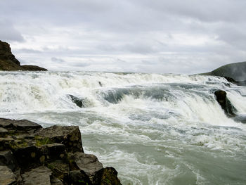 Scenic view of sea waves splashing against sky