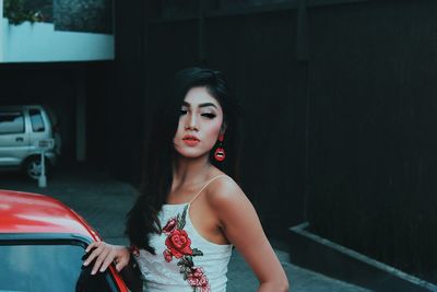 Young woman standing in red car