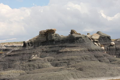 Low angle view of rock formations against cloudy sky