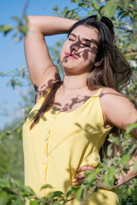 Portrait of young woman standing against plants