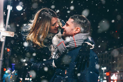 Couple romancing while standing against sky at night during winter