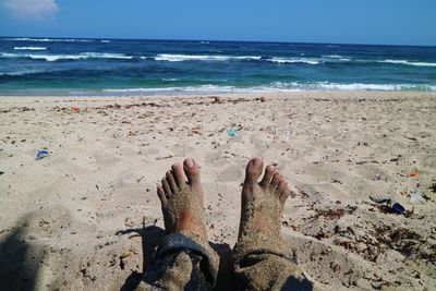 Low section of man on sand at beach