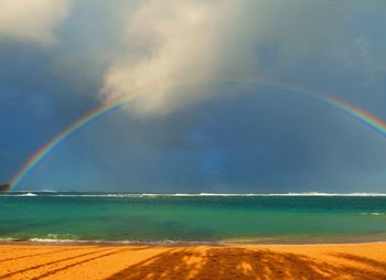 Scenic view of sea against rainbow in sky