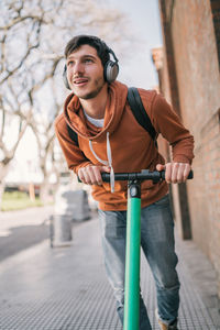 Young man holding camera while standing outdoors