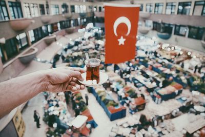 Cropped hand holding glass of tea against turkish flag