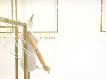 Woman standing on railing against white wall
