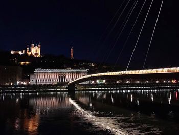 Illuminated bridge over river at night