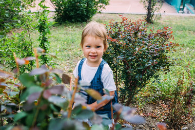 Little girl walks in the garden among beautiful evergreen southern plants