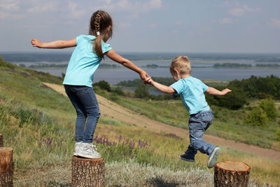 Full length of siblings walking on field