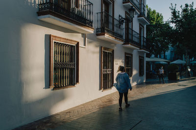 Rear view of man walking on street amidst buildings