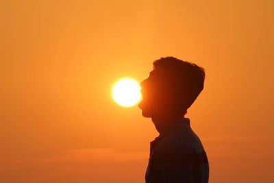 Silhouette of man against orange sky