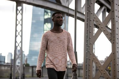 Young man looking away while walking on road