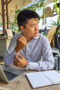 Young man using mobile phone while sitting on table