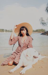 Portrait of young woman sitting at dog at beach