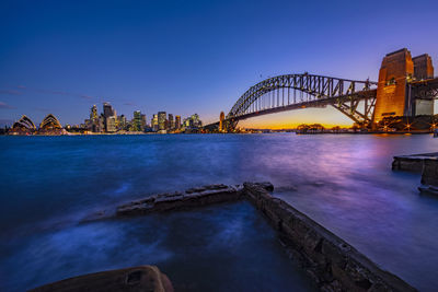 Bridge over sea in city at dusk