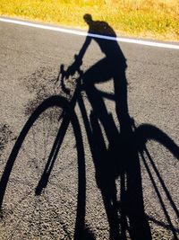 Shadow of man riding bicycle on road