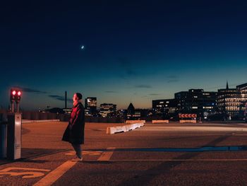 Man standing on road against illuminated city at night