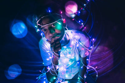 Full length of man sitting on floor with illuminated string light