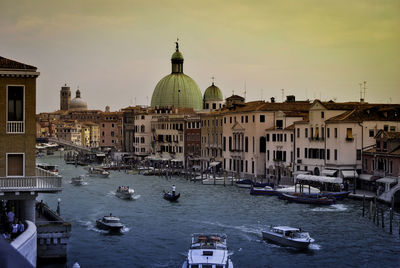 Boats moored in canal with city in background