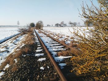 Snow covered railroad tracks against sky during winter