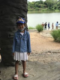 Full length portrait of girl standing near water