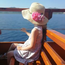 Midsection of woman sitting by railing against sea