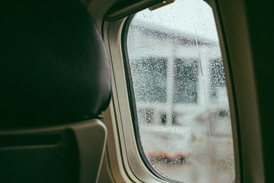 Close-up of vehicle seat by wet window in airplane