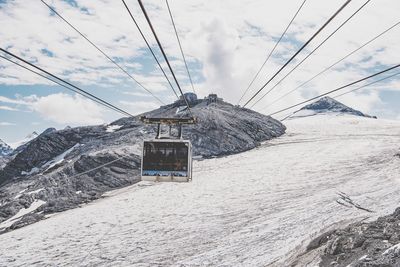 Cable car over snow covered land against sky