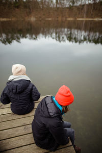 Rear view of people sitting by lake