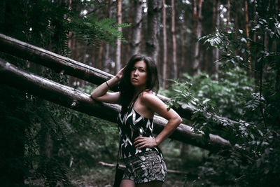 Portrait of woman standing by tree in forest