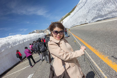 Portrait of woman in sunglasses standing on road during winter