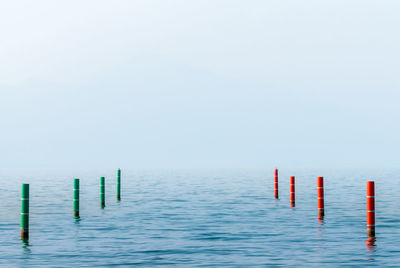 Wooden posts in sea against sky