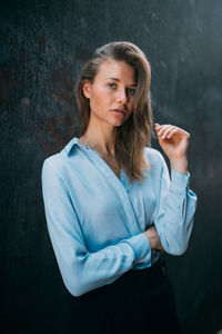 Portrait of a young woman standing against black background