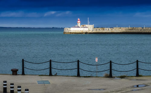 Lighthouse by sea against sky