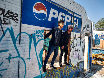 Full length of man standing against graffiti wall