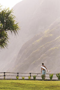 Young man walking and carrying surfboard