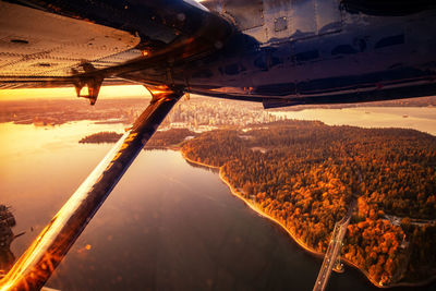 Aerial view of aircraft wing against sky during sunset