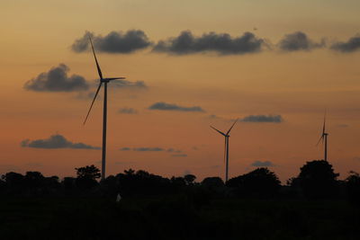 Silhouette windmill on field against romantic sky at sunset