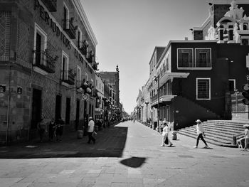 People walking on street amidst buildings in city