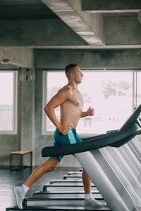 Shirtless man exercising on treadmill