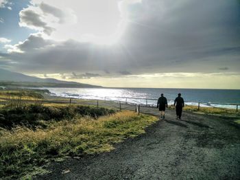 People walking on beach against sky