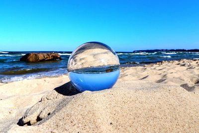 Close-up of water on beach against clear blue sky