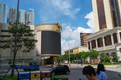 People on street by buildings against sky