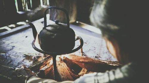 Rear view of woman by kettle on firewood stove