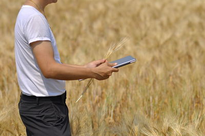 Midsection of man using mobile phone on field