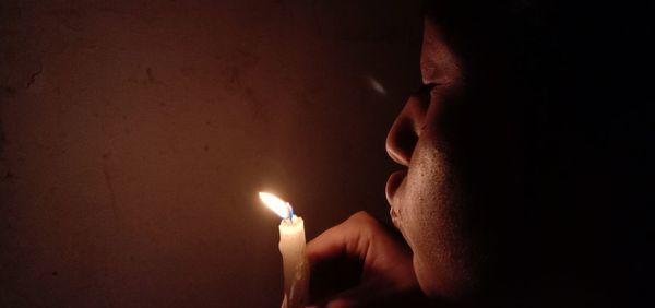 Close-up of lit candle in the dark