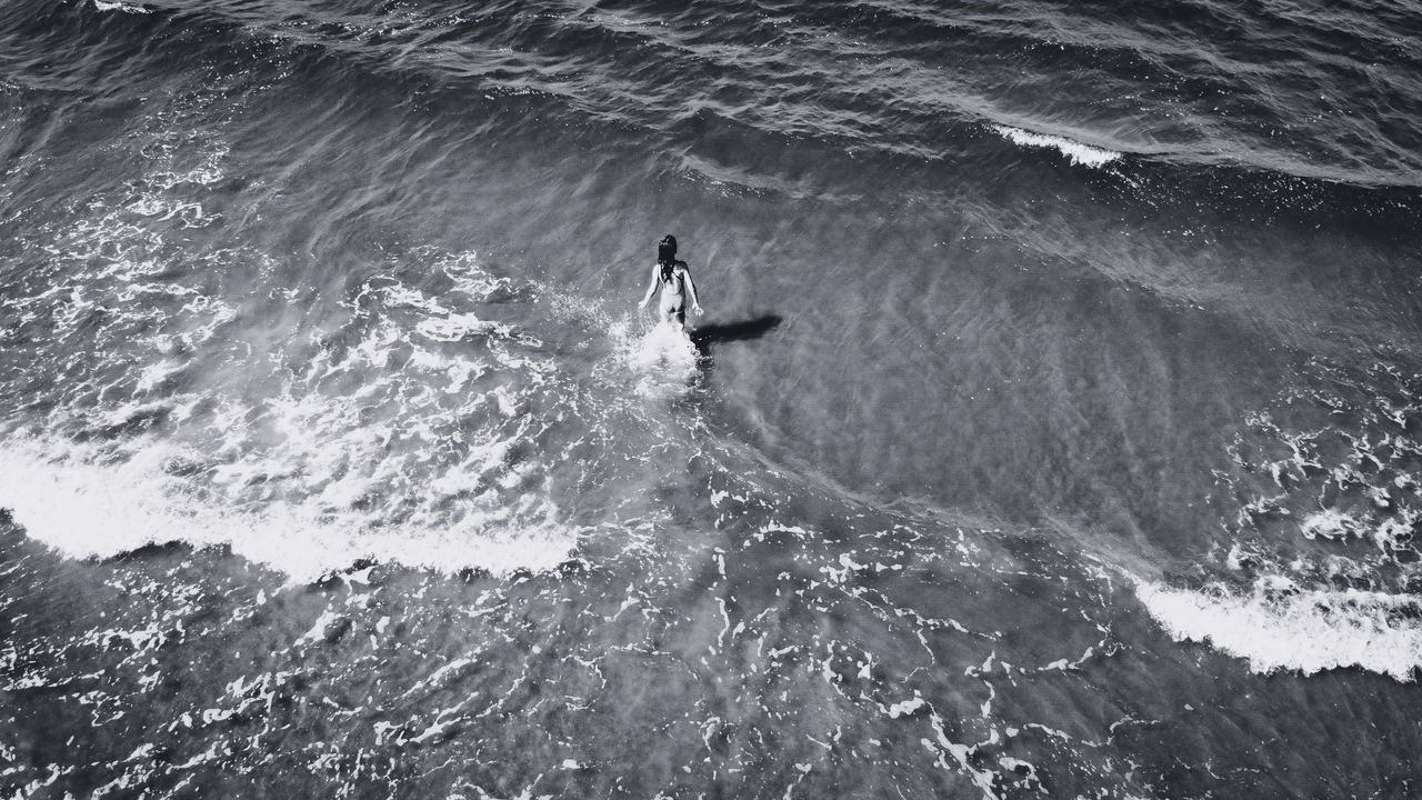 HIGH ANGLE VIEW OF MAN SURFING ON SEA