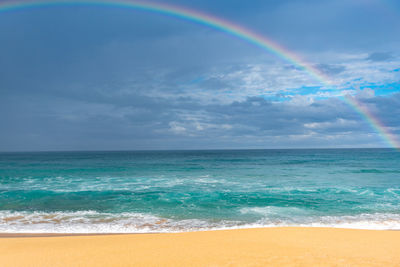 Scenic view of sea against rainbow in sky